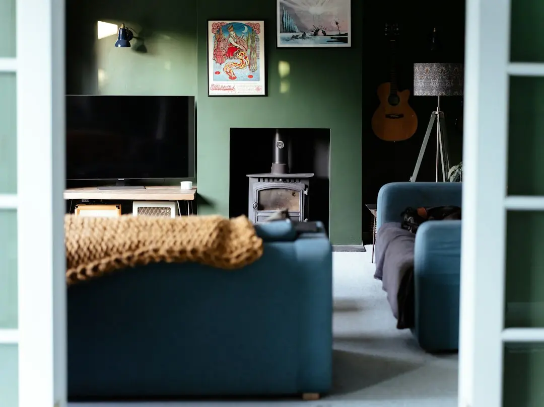 Een woonkamer met groene muren, een tv en een houtkachel, voor wie wil weten wat IPTV is en hoe Swivtv werkt
